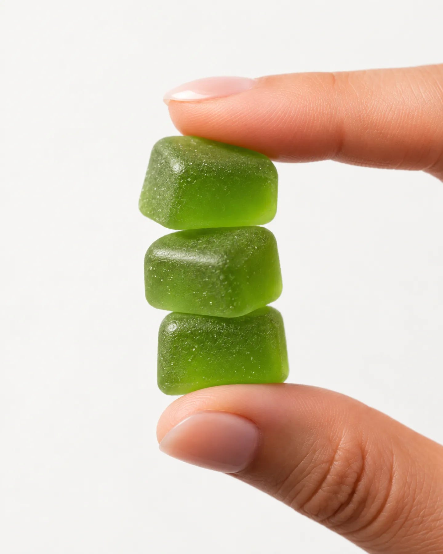 A stack of three Super Greens gummies between two fingers